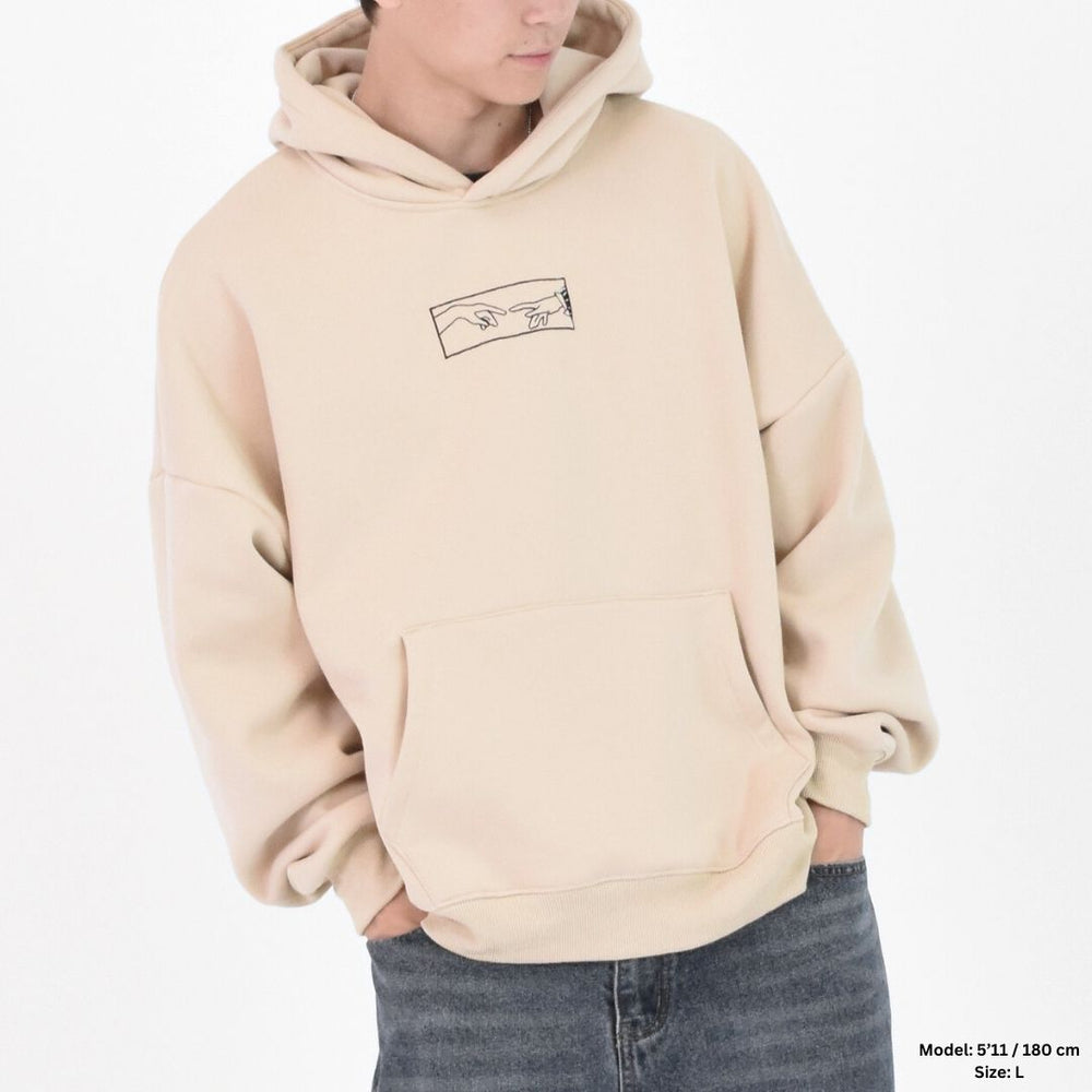 A person wearing a sand beige hoodie with a graphic and text on the back, over a white background.