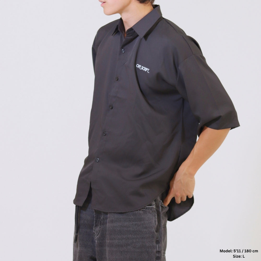 Person wearing a black shirt with a logo on a plain background