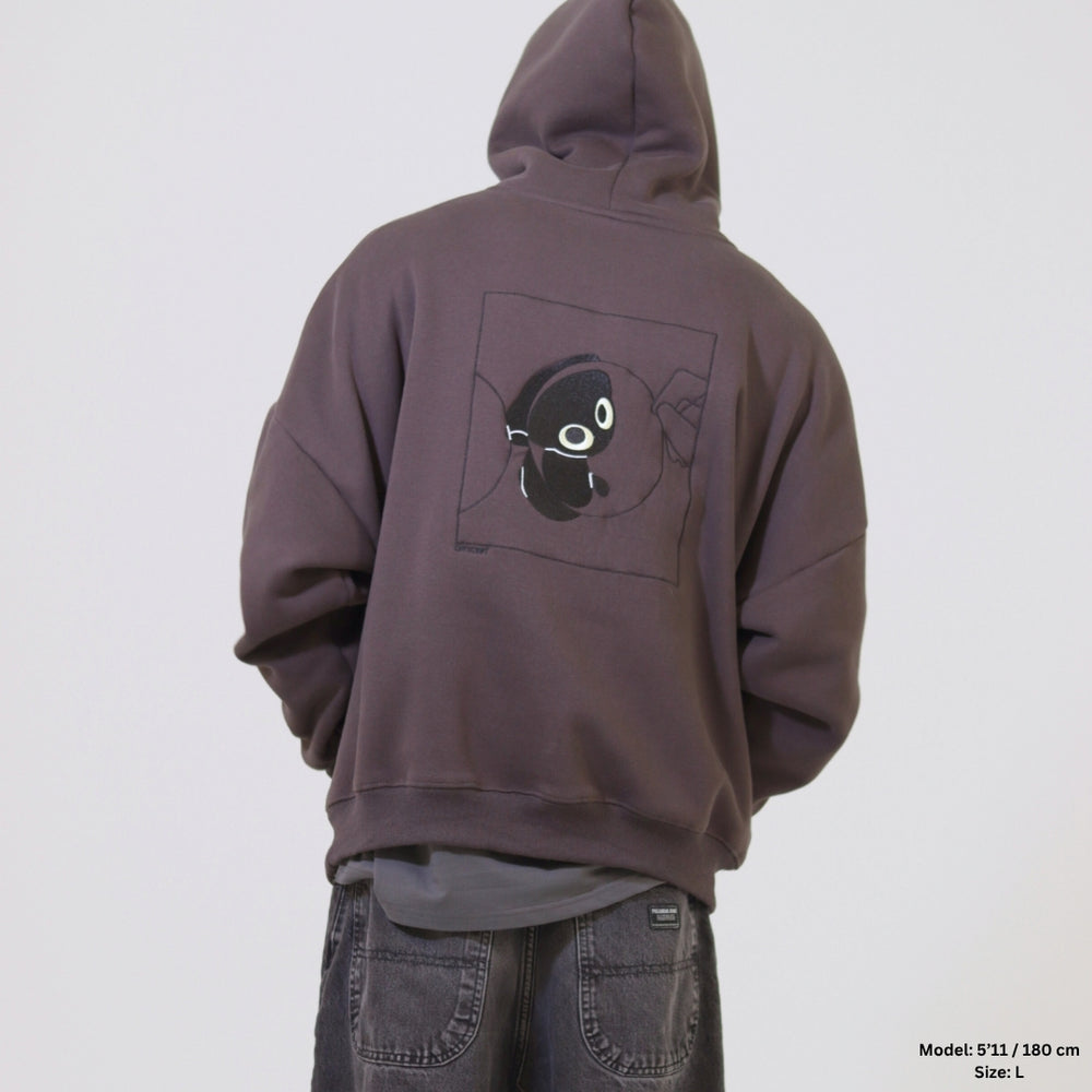 Person wearing a brown hoodie with a black graphic on the back against a white background