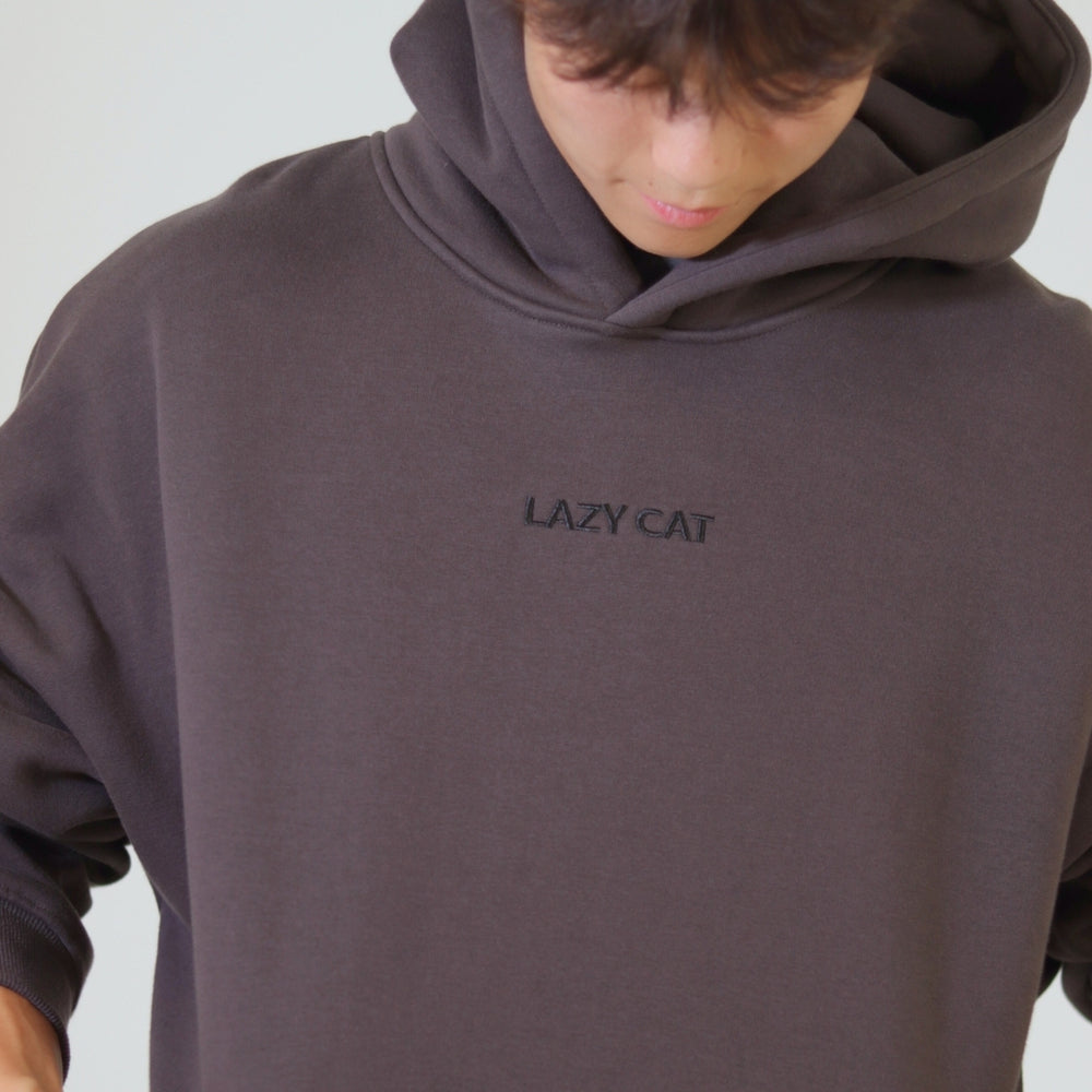 Person wearing a dark hoodie with 'LAZY CAT' text on a light gray background