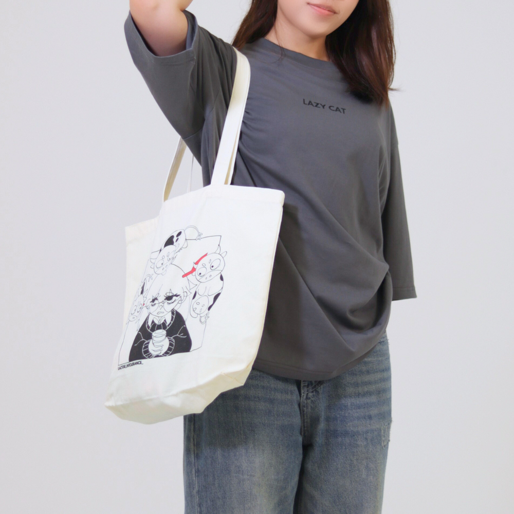 Person holding a white tote bag with black graphics against a plain background