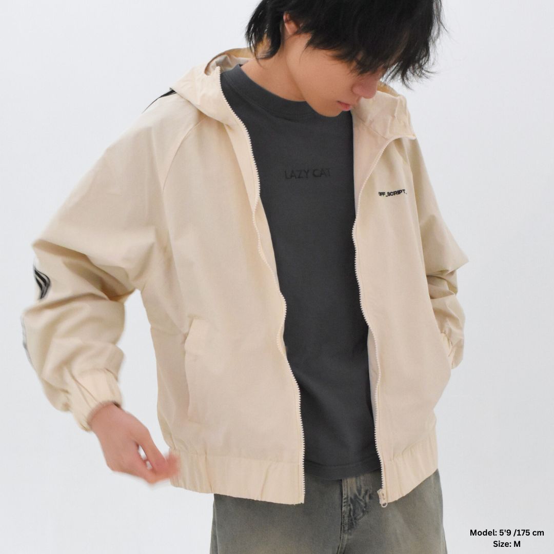 Person wearing a beige jacket over a black shirt on a white background