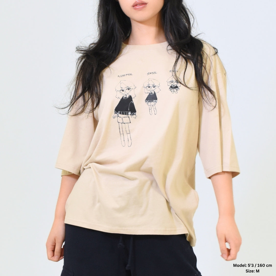 Woman wearing a beige oversized shirt with graphic designs on a plain background