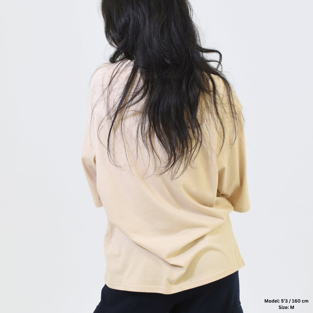 Person wearing a beige sweater with long dark hair on a white background