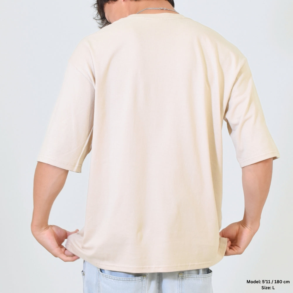 Person wearing a beige t-shirt against a plain background