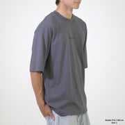 Person wearing a gray t-shirt with a brand logo on a white background