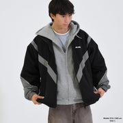 Person wearing a black and gray jacket with a brand logo on a white background