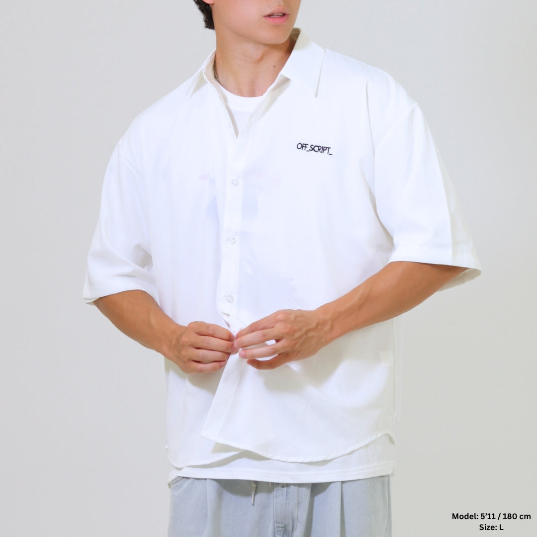 Person wearing a white shirt with a brand logo on a plain background
