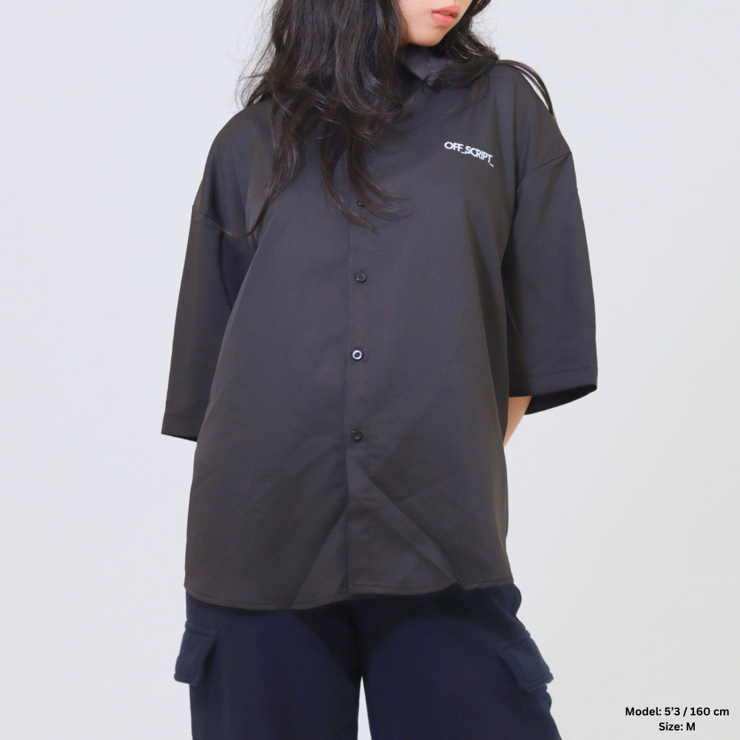 Person wearing a black oversized shirt with a brand logo on a white background
