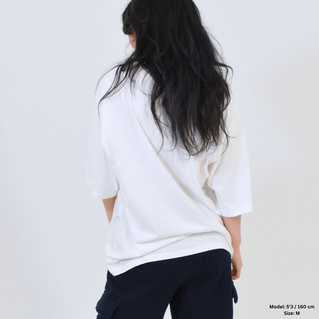 Person wearing a white shirt and dark pants against a plain background
