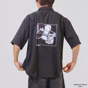 Person wearing a black shirt with a graphic design on the back against a plain background