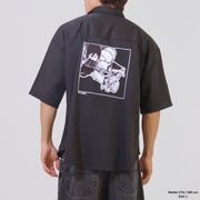Person wearing a black short-sleeve shirt with a graphic on the back against a plain background