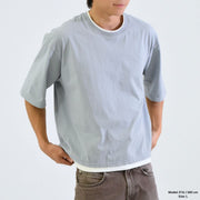 Person wearing a plain light gray t-shirt on a white background