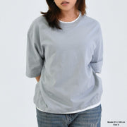 Person wearing a light gray oversized shirt on a plain background