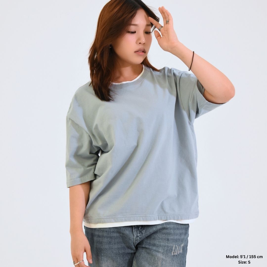 Woman wearing a light gray oversized t-shirt against a white background