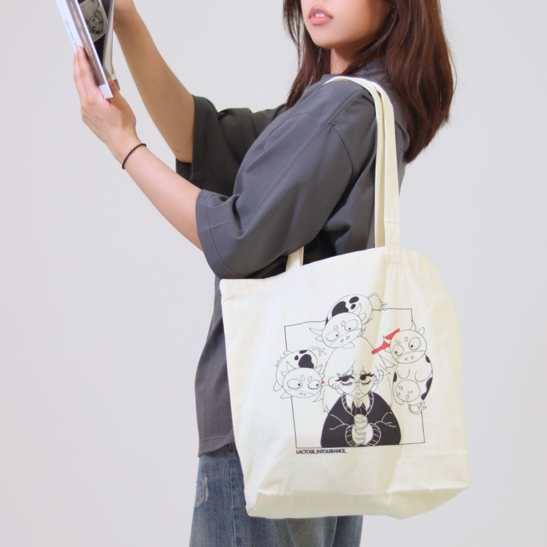 Person holding a tote bag with cartoon designs on a plain background
