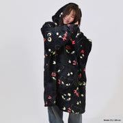 Person wearing a black coat with cat face patterns on a plain background