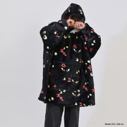 Person wearing a black hoodie with colorful cat face patterns on a white background