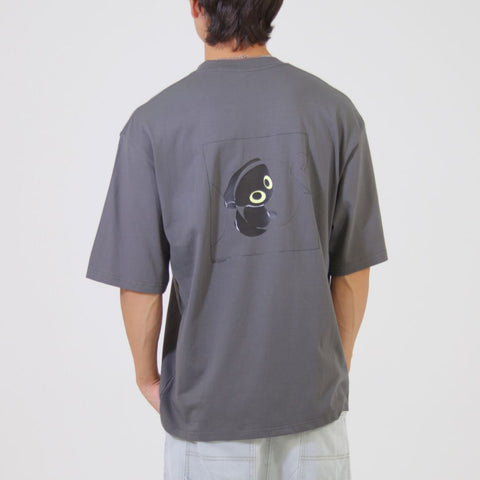 Person wearing a gray t-shirt with a graphic design on the back against a plain background